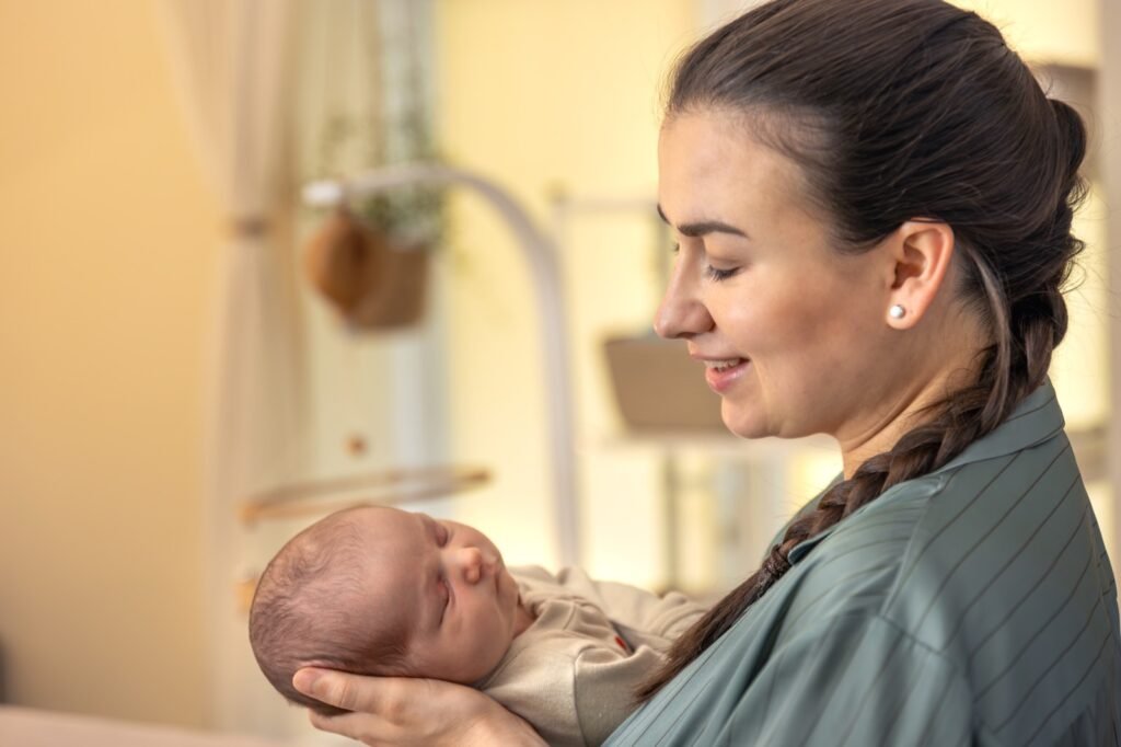 Mother gently cradling her newborn baby in soft warm light – infant feeding and breastfeeding support